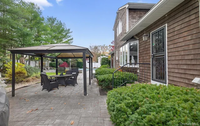 a view of a patio with a table and chairs under an umbrella with a large tree