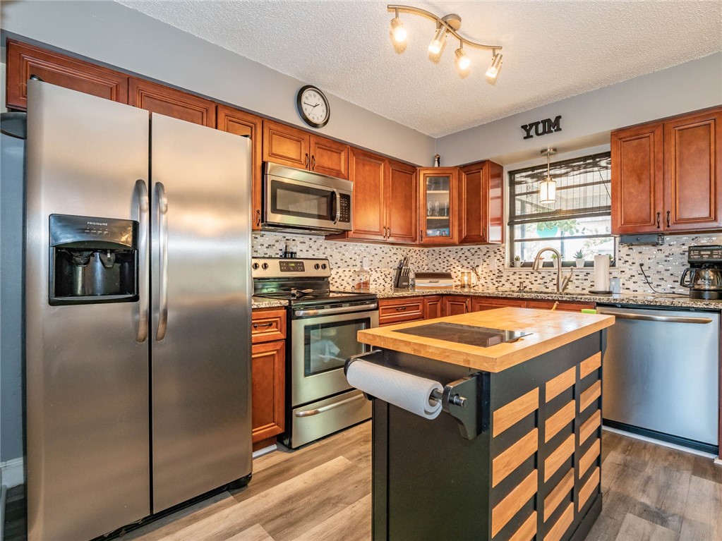 438 Columbus Street Sebastian, FL 32958 - Photo 11 of 32 a kitchen with stainless steel appliances granite countertop a refrigerator a sink dishwasher a stove with wooden cabinets and floor