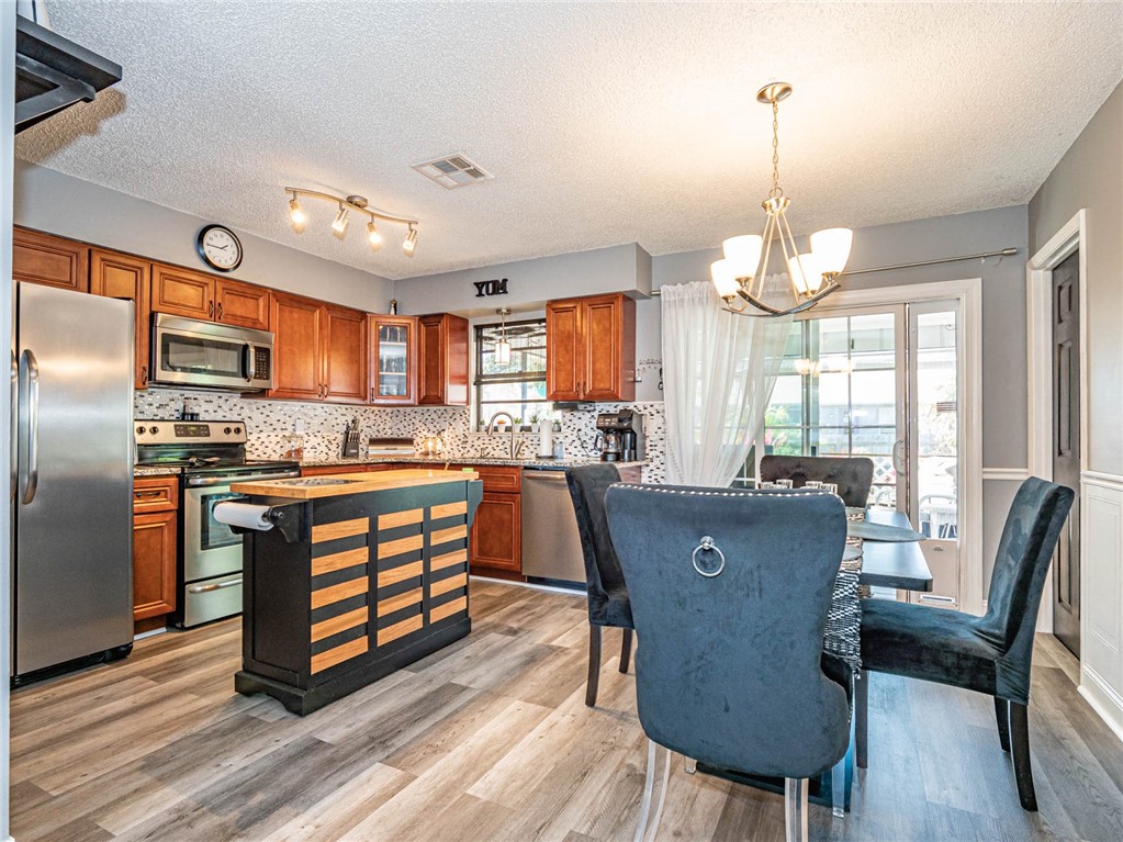 438 Columbus Street Sebastian, FL 32958 - Photo 5 of 32 a kitchen with stainless steel appliances granite countertop a refrigerator a stove a sink dishwasher a dining table and chairs with wooden floor