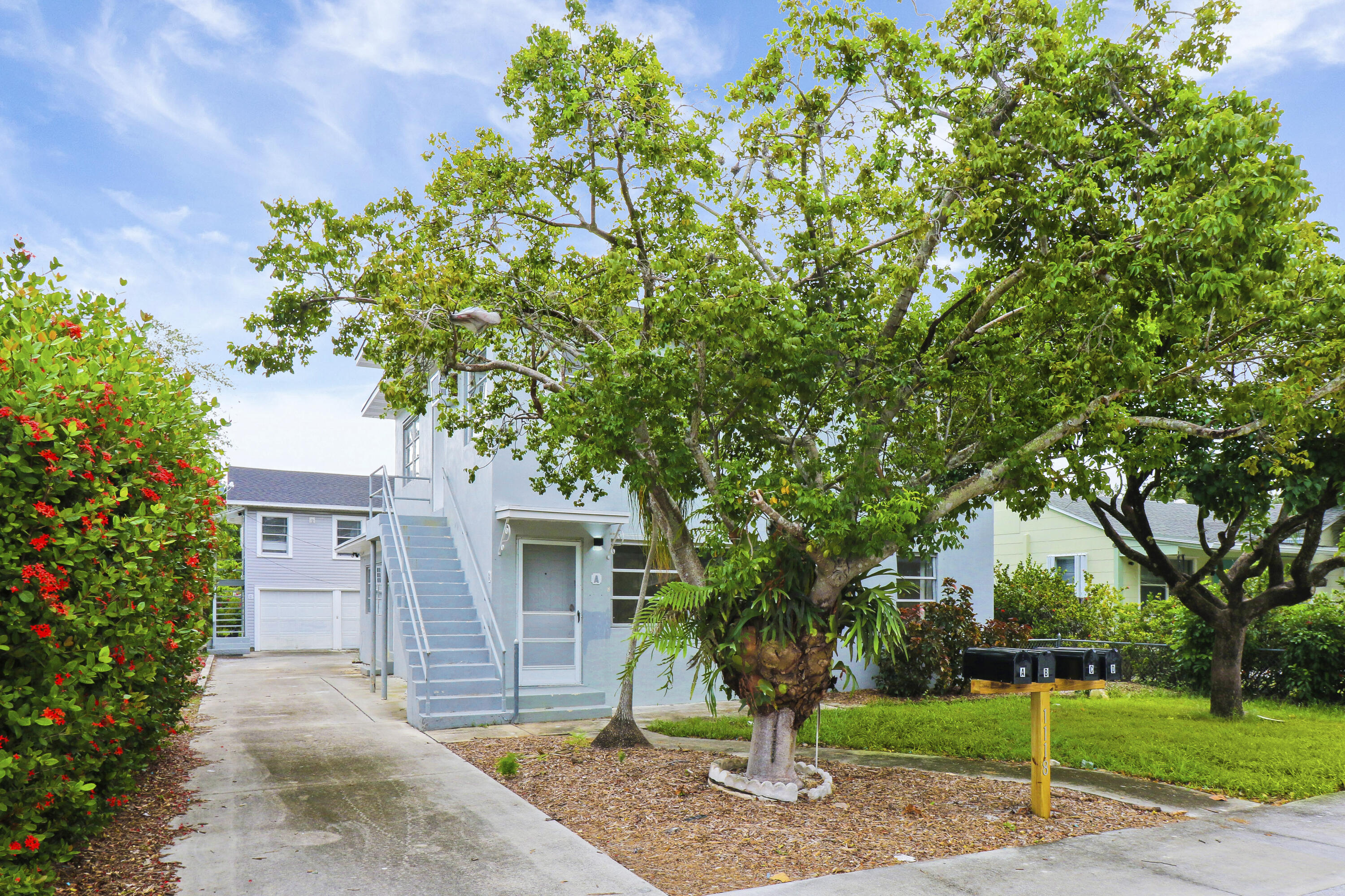 a front view of a house with a garden and trees