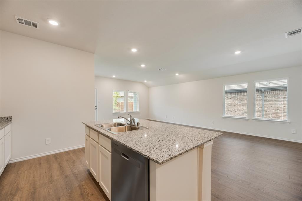3407 Rendezvous Way Sherman, TX 75090 - Photo 8 of 17 Kitchen island with a double basin stainless steel sink, a stainless steel dishwasher, and a light-toned countertop
