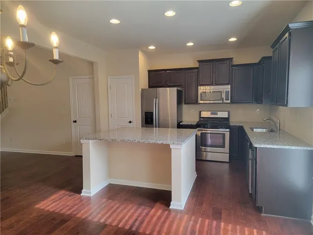 a kitchen with kitchen island a counter top space a sink stainless steel appliances and cabinets