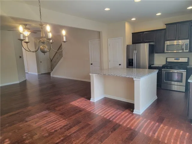 a kitchen with stainless steel appliances a refrigerator and a wooden floor