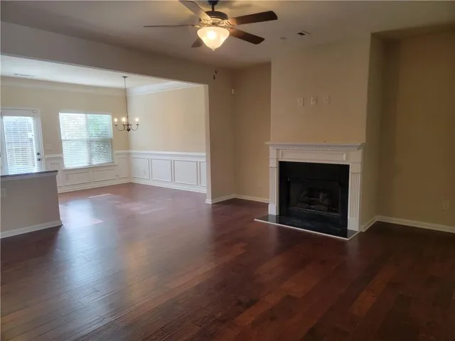 an empty room with wooden floor fireplace and windows