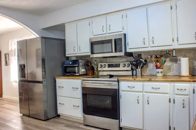 a kitchen with cabinets stainless steel appliances and wooden floors