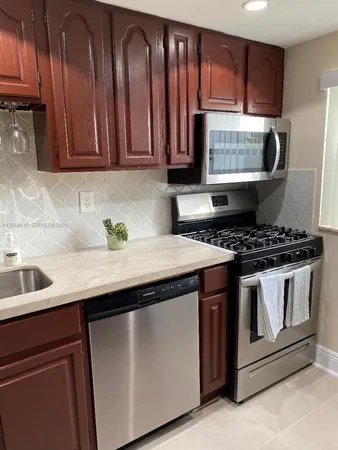 a kitchen with granite countertop stainless steel appliances a sink stove and cabinets