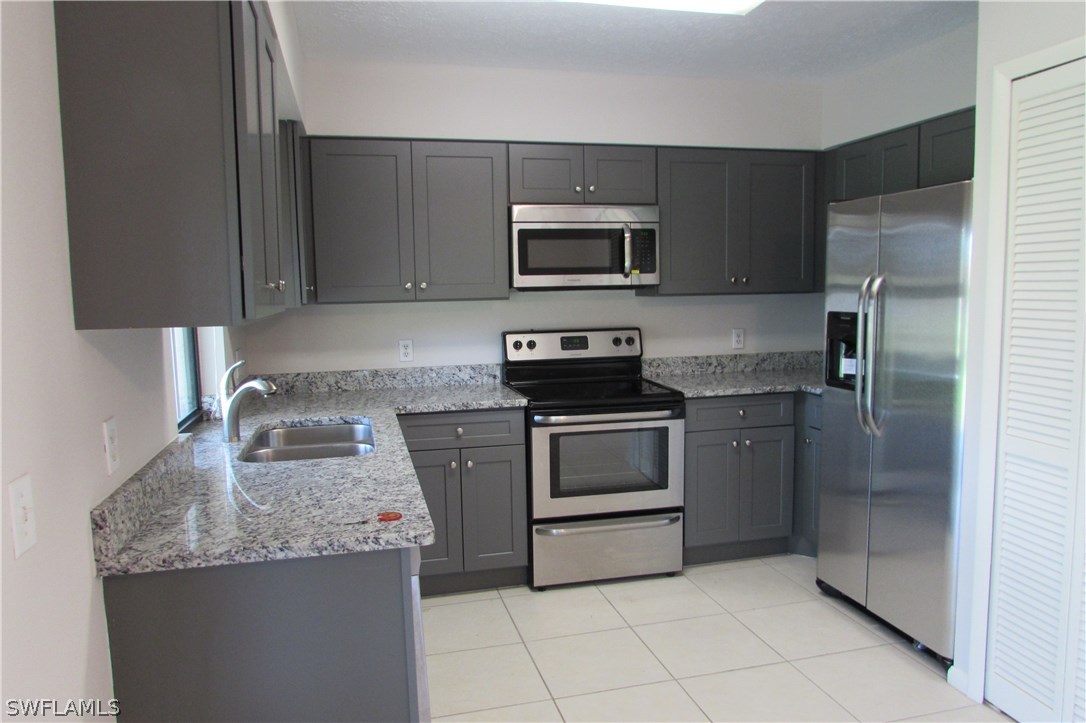 4983 18th Court Southwest Naples, FL 34116 - Photo 6 of 25 a kitchen with stainless steel appliances granite countertop a sink stove and refrigerator