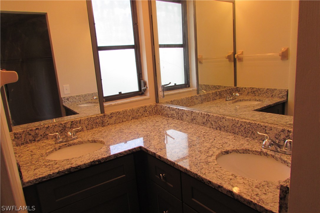 4983 18th Court Southwest Naples, FL 34116 - Photo 7 of 25 a bathroom with a granite countertop sink and a large mirror