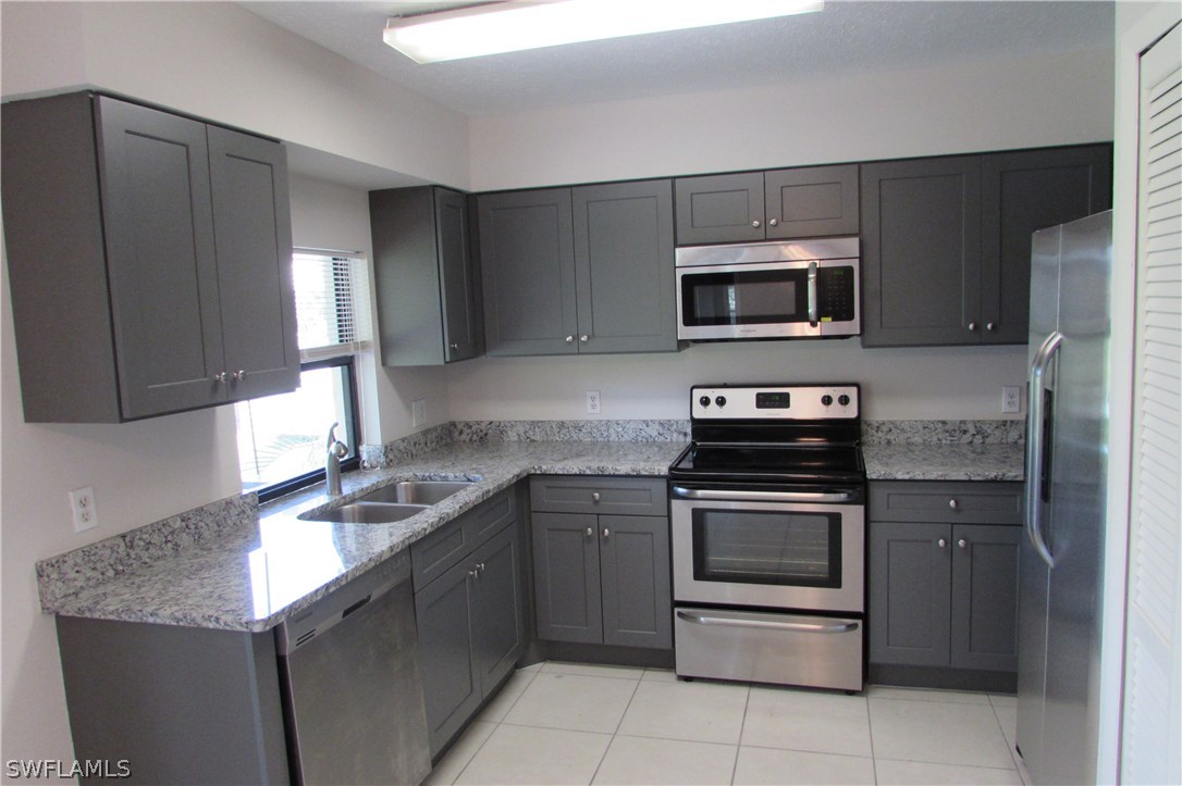 4983 18th Court Southwest Naples, FL 34116 - Photo 8 of 25 a kitchen with stainless steel appliances granite countertop a stove microwave and sink