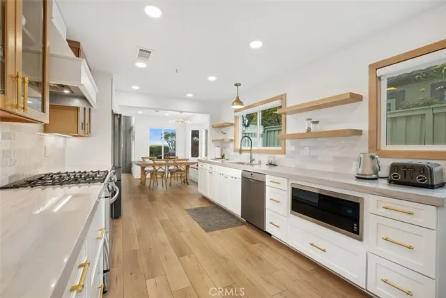 a kitchen with stainless steel appliances granite countertop a stove top oven a sink a dining table and chairs