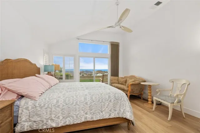 a bedroom with a bed a chair and potted plant on the dresser