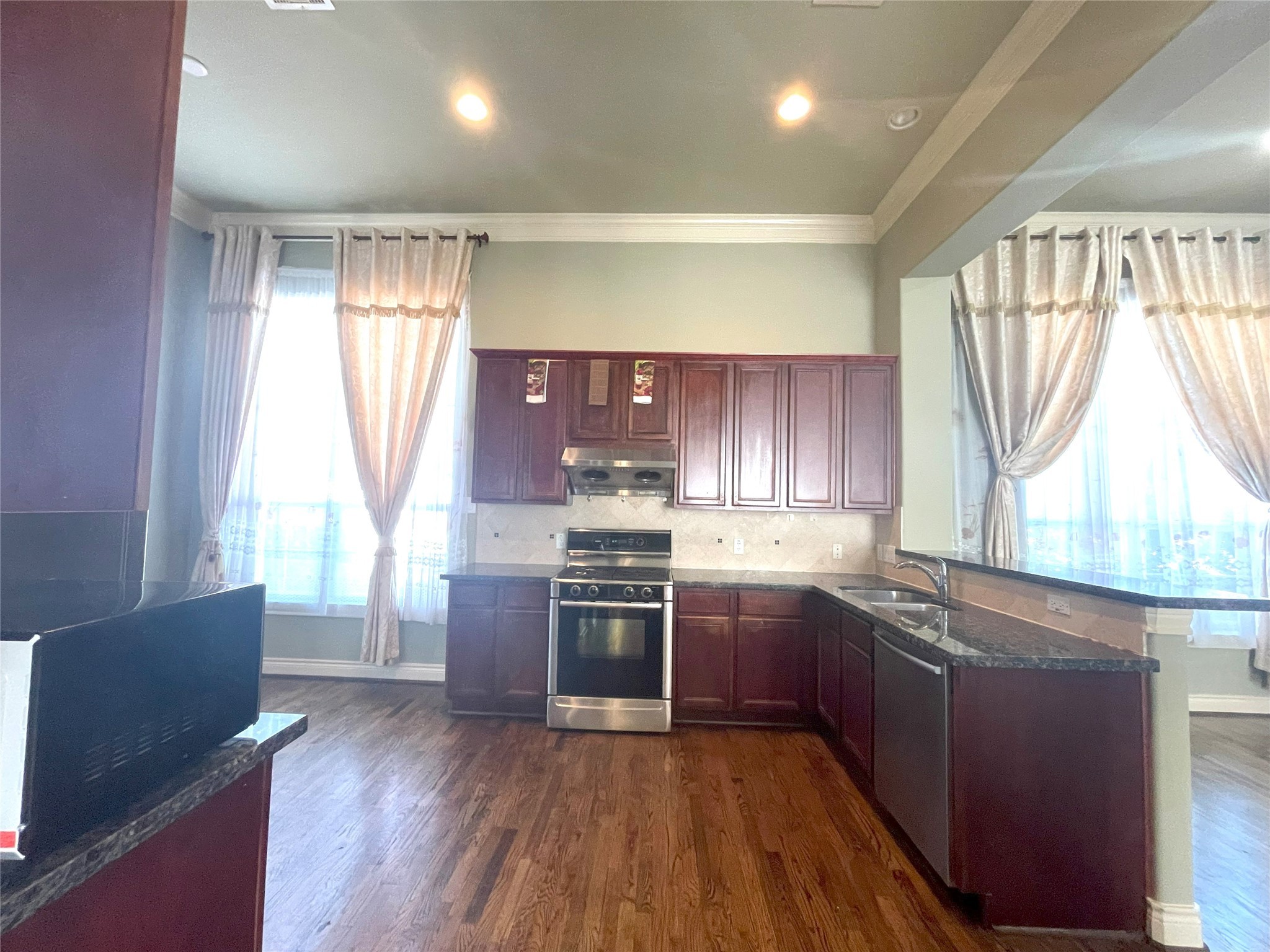 3138 Pemberton Walk Houston, TX 77025 - Photo 16 of 27 a kitchen with stainless steel appliances granite countertop hardwood floor sink stove and wooden cabinets