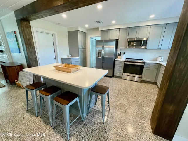 a kitchen with stainless steel appliances kitchen island granite countertop a table chairs sink and cabinets