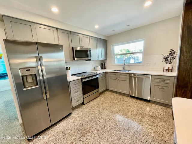 a kitchen with stainless steel appliances a sink a stove a microwave a refrigerator a sink and cabinets