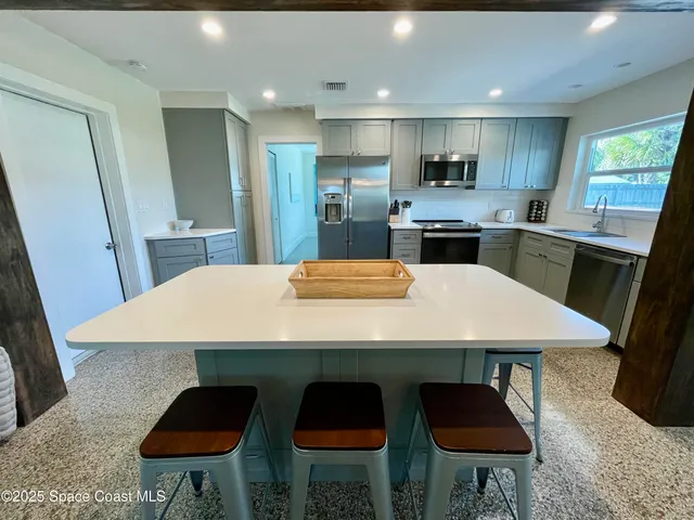 a kitchen with stainless steel appliances a table chairs in it and wooden floors