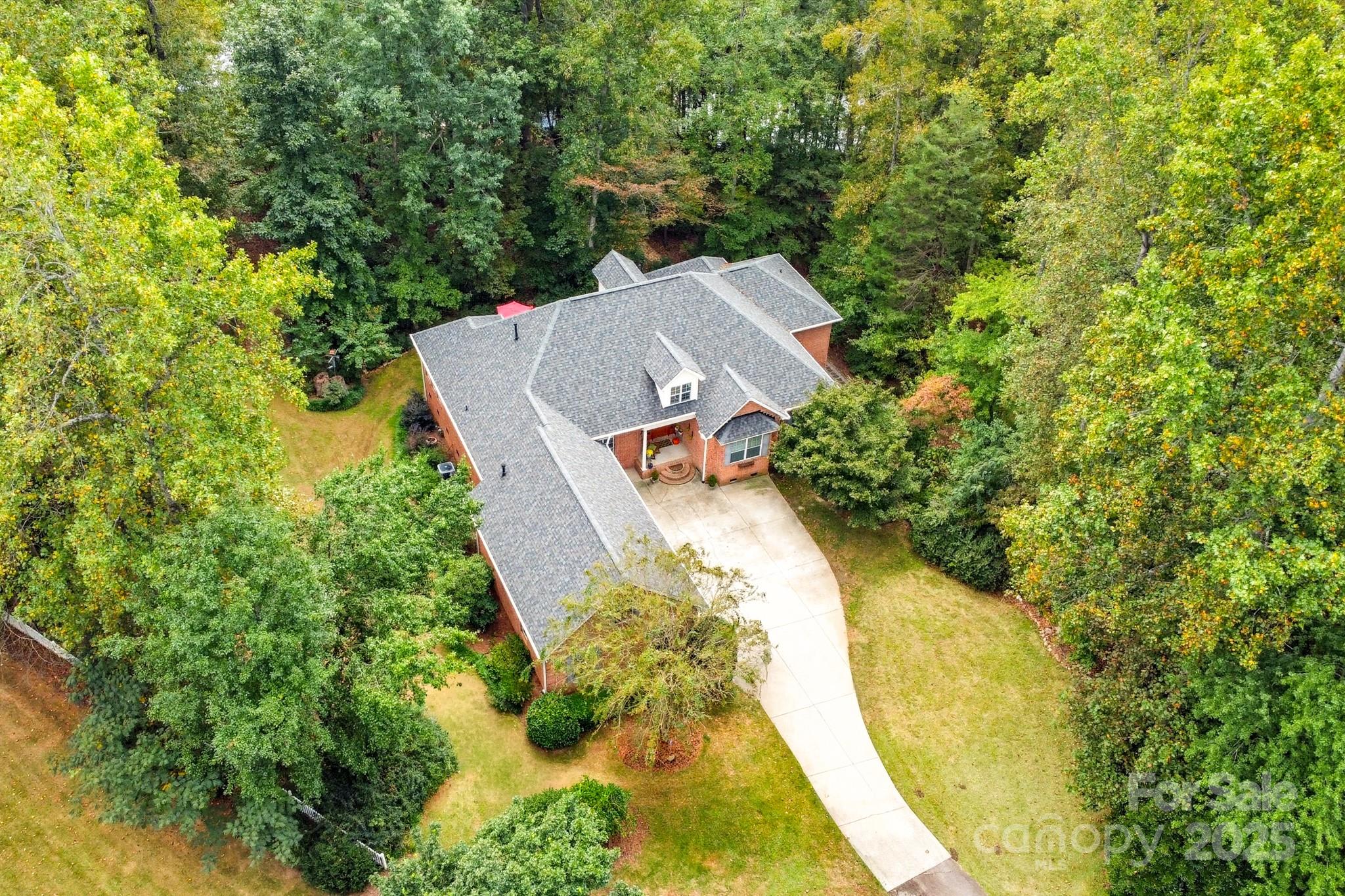 an aerial view of a house with swimming pool and large trees