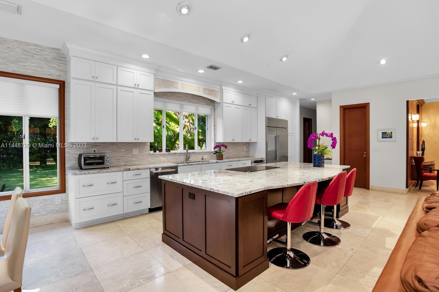 9718 Southwest 58th Court Pinecrest, FL 33156 - Photo 15 of 35 a kitchen with stainless steel appliances kitchen island granite countertop a table and chairs in it