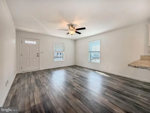 a view of an empty room with a window and wooden floor