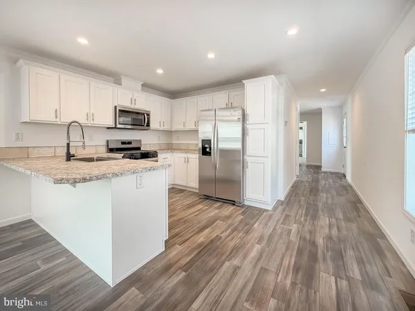 a kitchen with stainless steel appliances granite countertop a refrigerator a stove top oven a sink and dishwasher with wooden floor