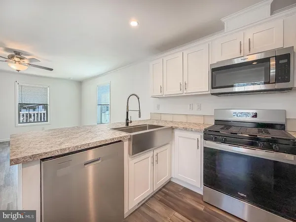 a kitchen with stainless steel appliances granite countertop a stove a microwave and white cabinets