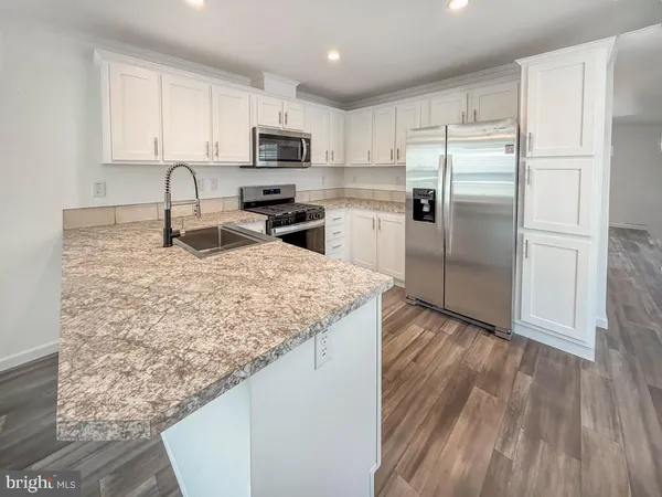 a kitchen with kitchen island granite countertop a sink refrigerator and microwave