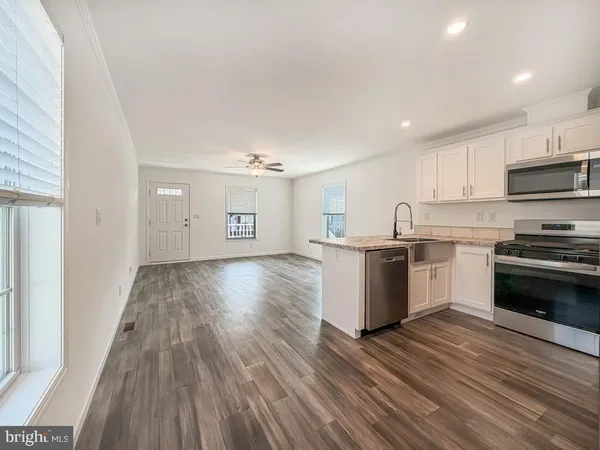 a kitchen with wooden floors and white stainless steel appliances