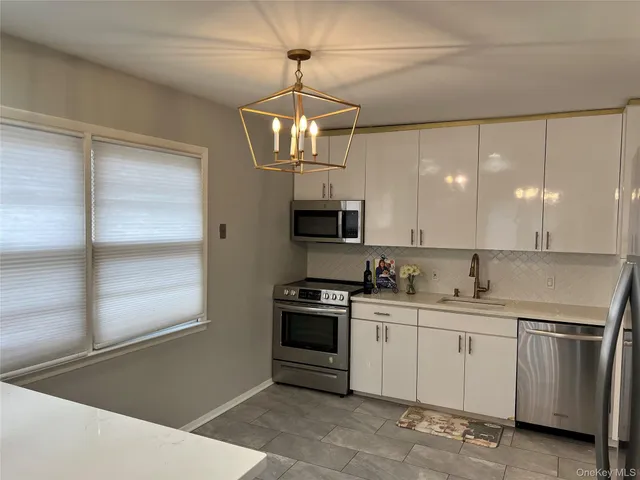 a kitchen with granite countertop white cabinets and stainless steel appliances