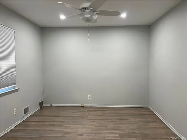 a view of an empty room with wooden floor and closet