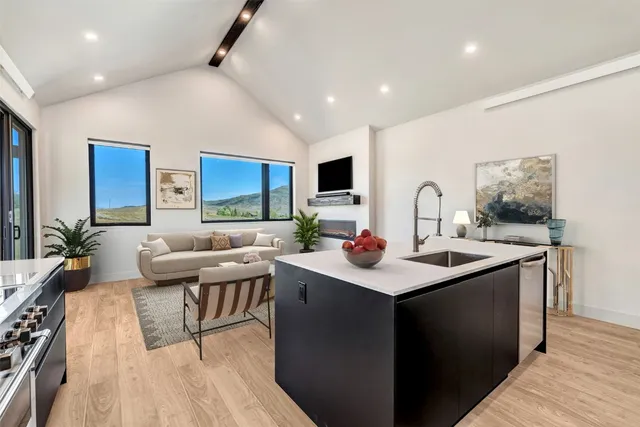 a kitchen with a sink and white cabinets with wooden floor