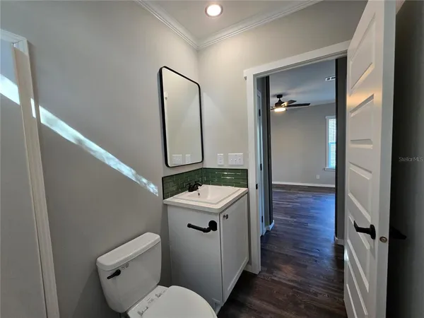a bathroom with a toilet a sink and wooden floor