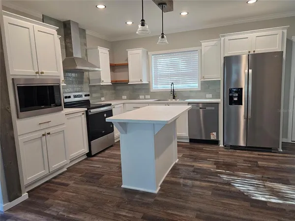 a large kitchen with stainless steel appliances granite countertop a stove a sink dishwasher and a refrigerator