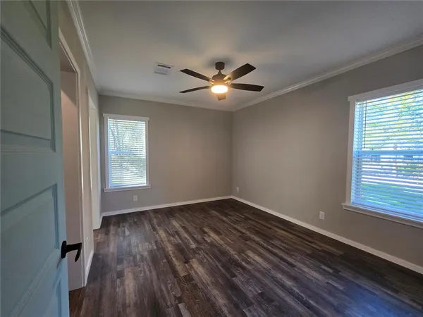 a view of empty room with wooden floor and fan