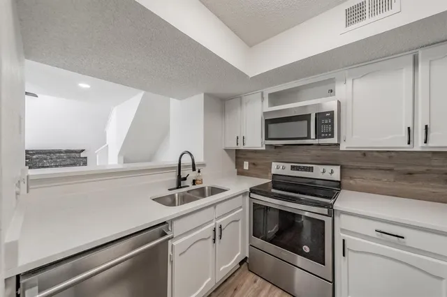 a kitchen with appliances a sink and cabinets