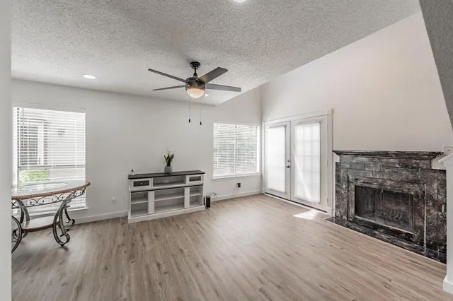 an empty room with windows a fireplace and wooden floor