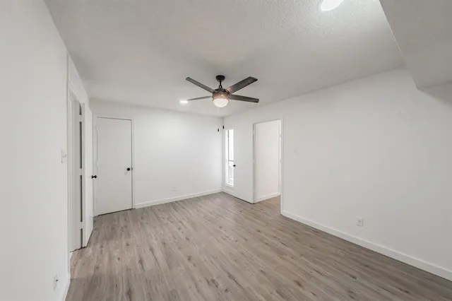 an empty room with wooden floor and a ceiling fan