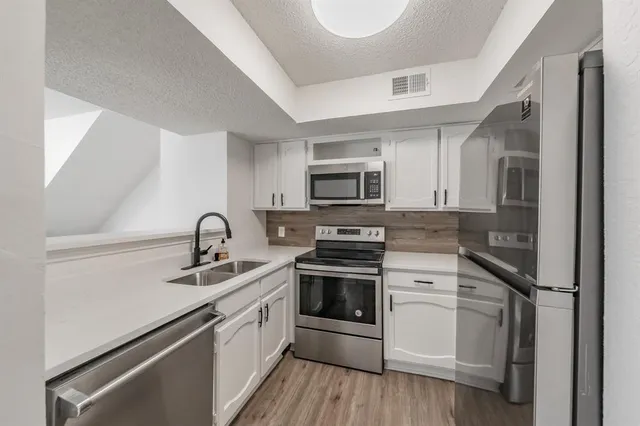 a kitchen with a sink white cabinets and stainless steel appliances