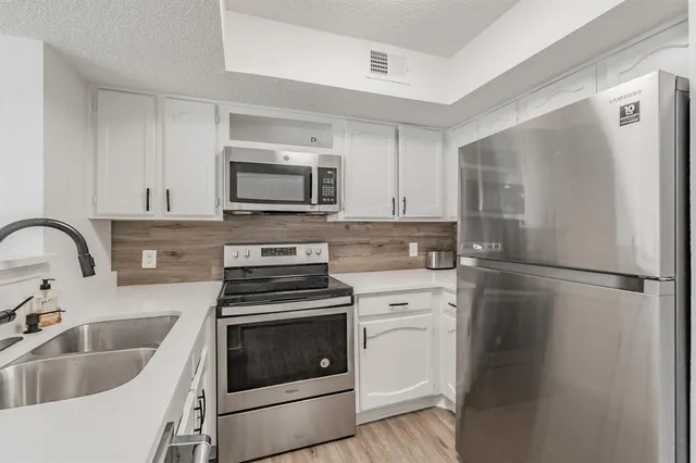 a kitchen with white cabinets and stainless steel appliances