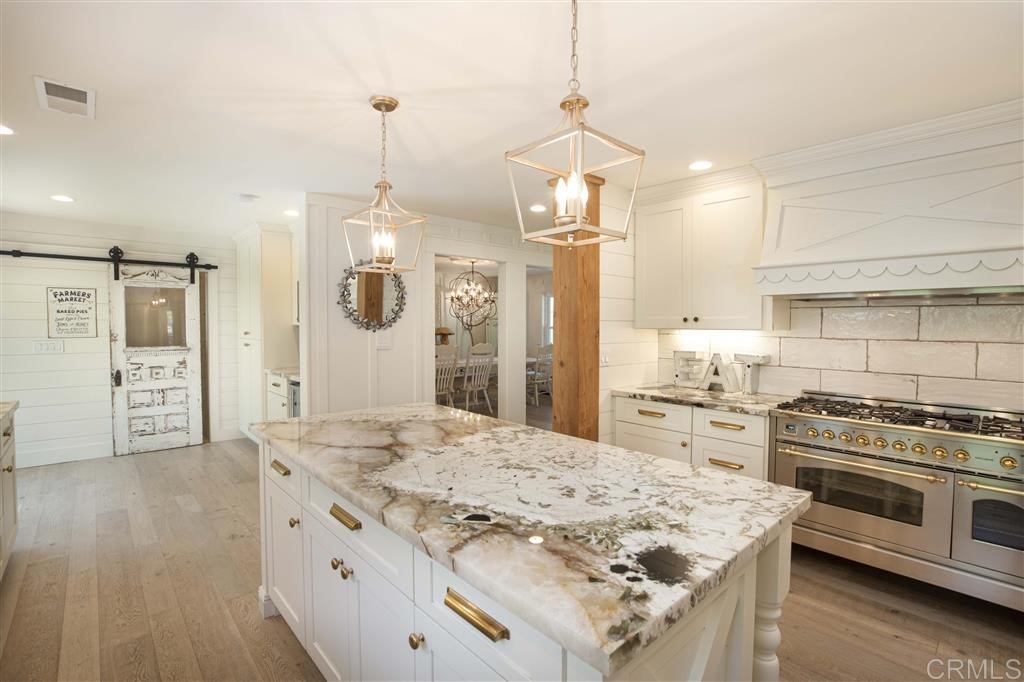 3945 Pala Mesa Drive Fallbrook, CA 92028 - Photo 4 of 23 a kitchen with stainless steel appliances kitchen island granite countertop a stove a sink a refrigerator and a wooden floor