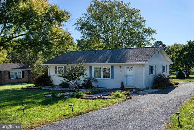 a front view of a house with a garden and trees