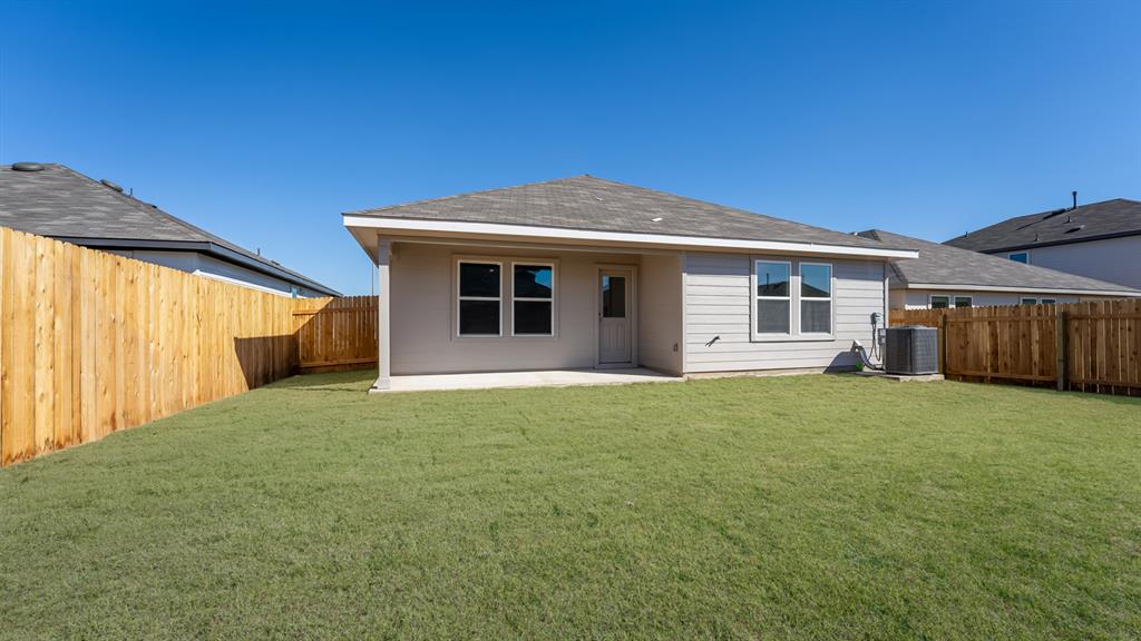 14021 Feinstein Street Manor, TX 78653 - Photo 23 of 25 A neatly fenced yard offers private outdoor enjoyment, featuring a freshly poured patio slab.