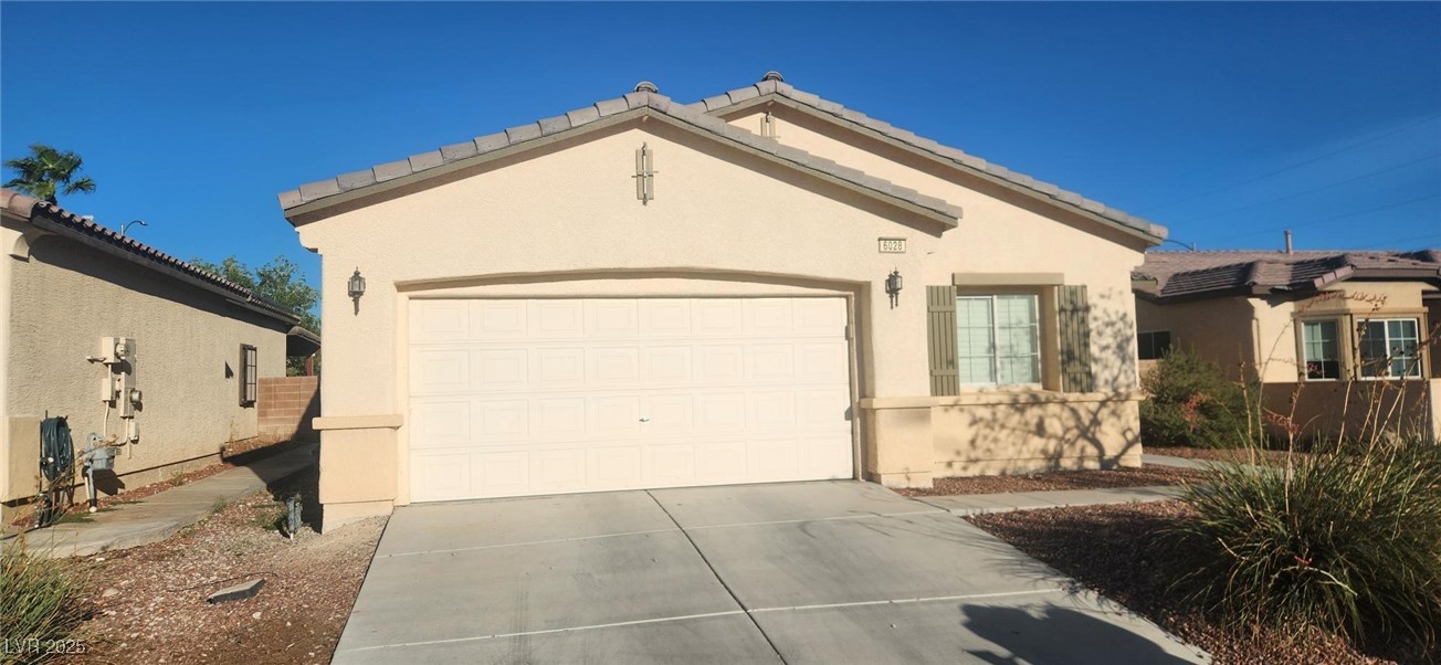 View of front of property with driveway, stucco siding, an attached garage, and a tiled roof