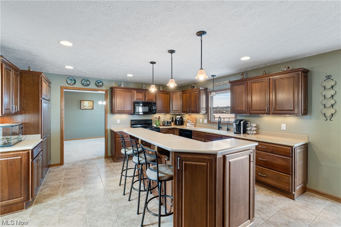 4363 Wile Road Wooster, OH 44691 - Photo 9 of 36 Kitchen with black appliances, a kitchen island, pendant lighting, light tile flooring, and a textured ceiling