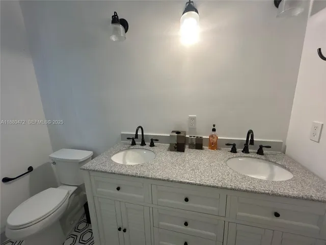 a bathroom with a granite countertop toilet sink and mirror