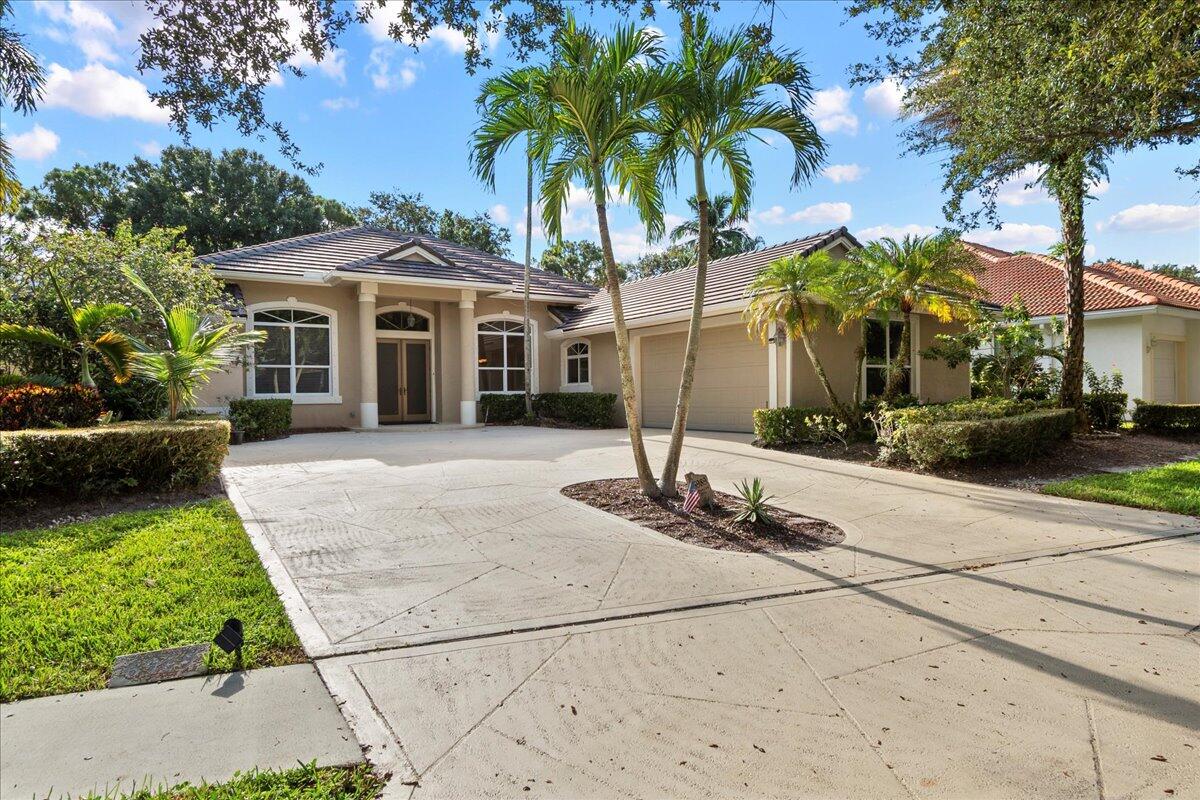 6989 Cypress Cove Circle Jupiter, FL 33458 - Photo 1 of 47 a front view of a house with garden and trees