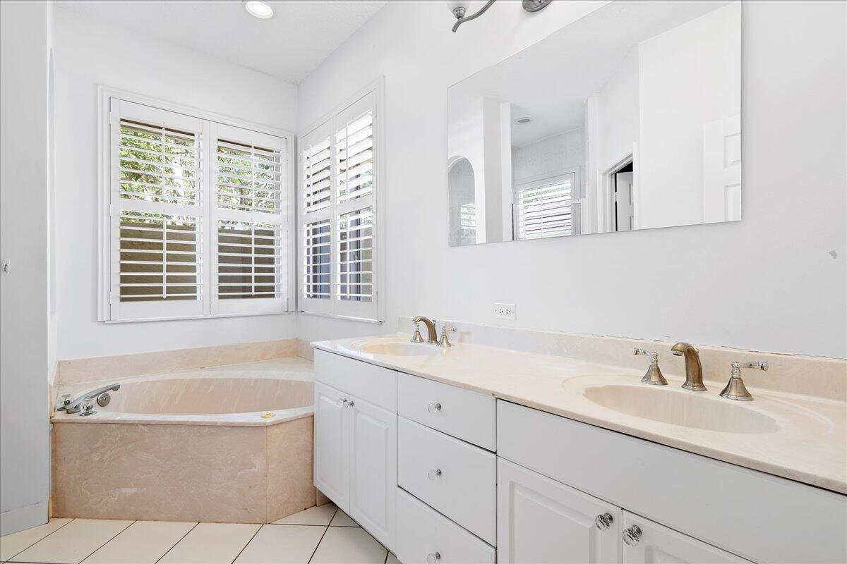 6989 Cypress Cove Circle Jupiter, FL 33458 - Photo 29 of 47 a bathroom with a tub sink and mirror