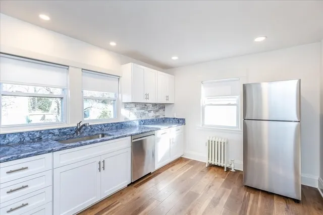 a kitchen with a refrigerator a sink and wooden floor