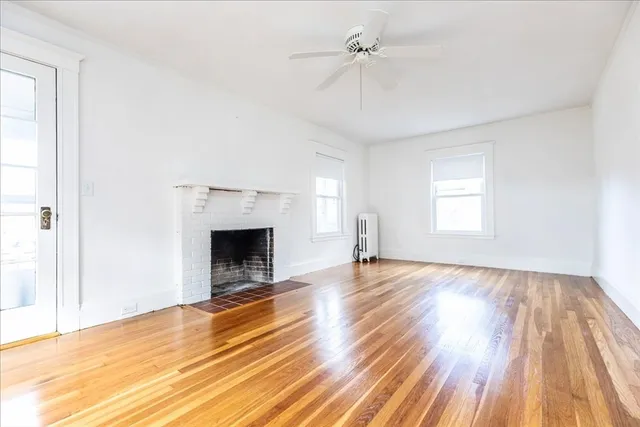 a view of empty room with a fireplace and wooden floor