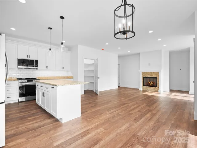 a kitchen with stainless steel appliances granite countertop a stove oven and a wooden floors