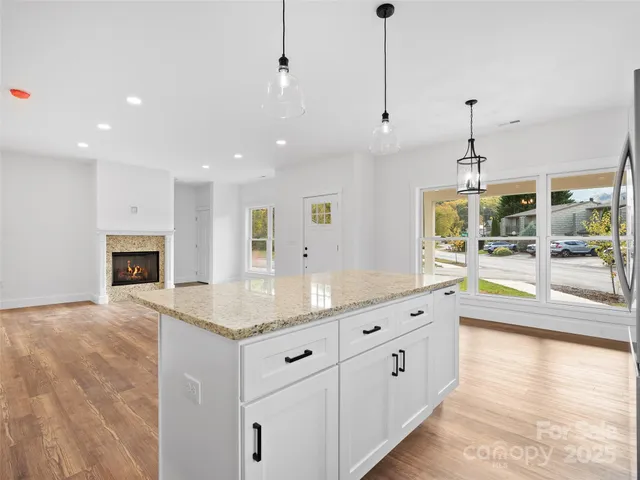 a large kitchen with kitchen island a stove a sink a center island and wooden floor