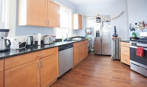 a kitchen with stainless steel appliances granite countertop a refrigerator a sink dishwasher and white cabinets with wooden floor